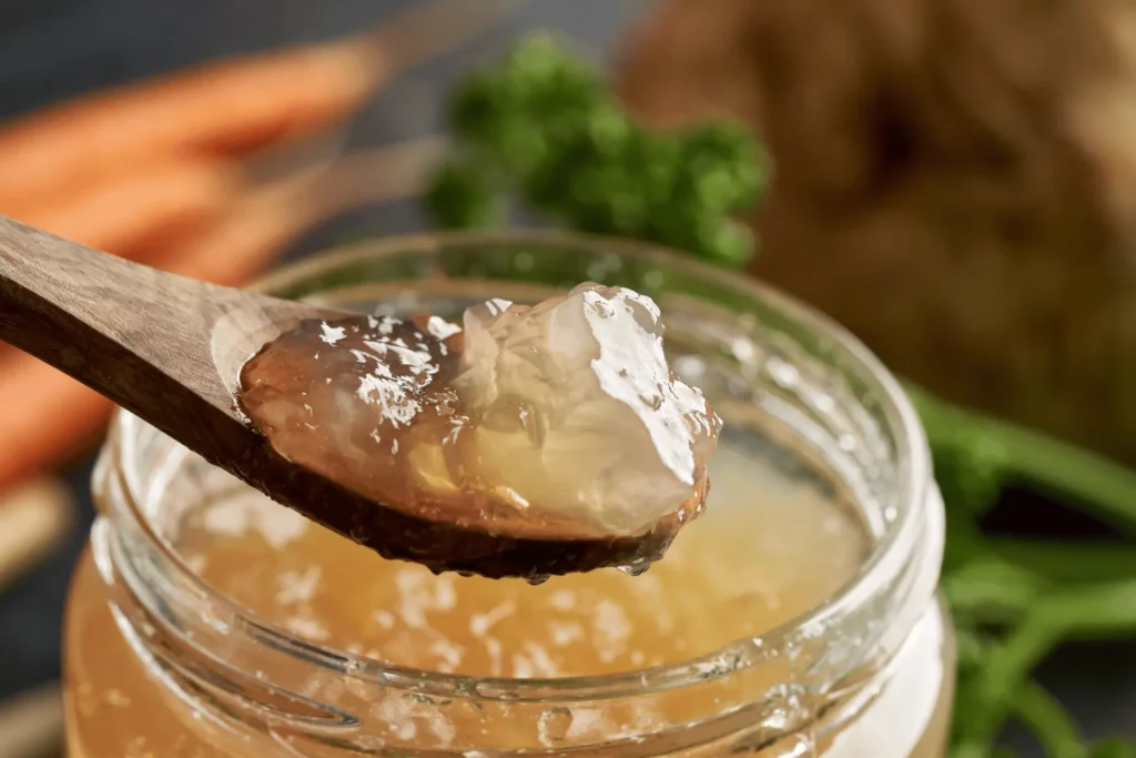 Nutritious homemade bone broth in a jar with a spoon scooping out a serving